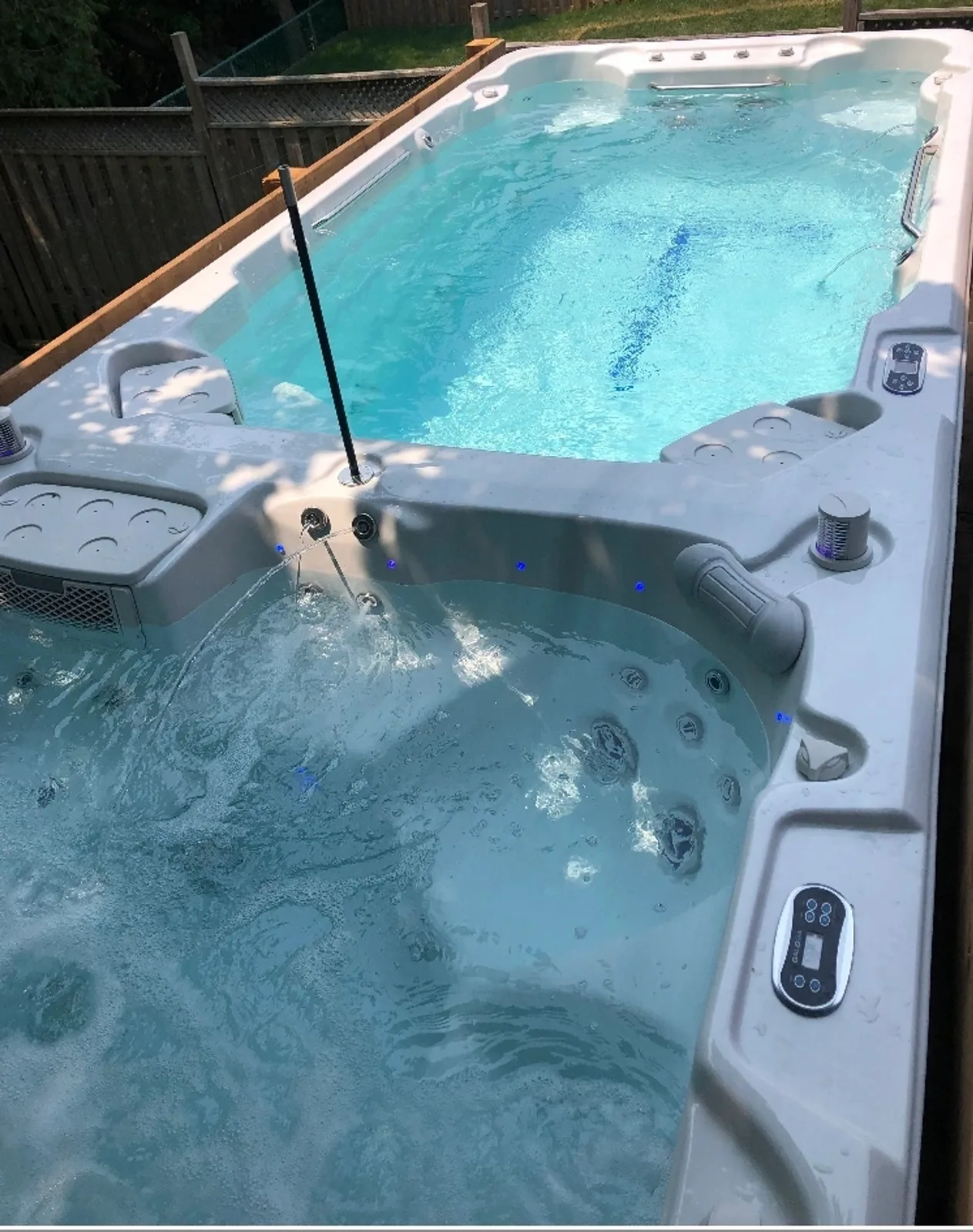 A Courtyard swim spa installed in a customer's backyard, lit at the waterline